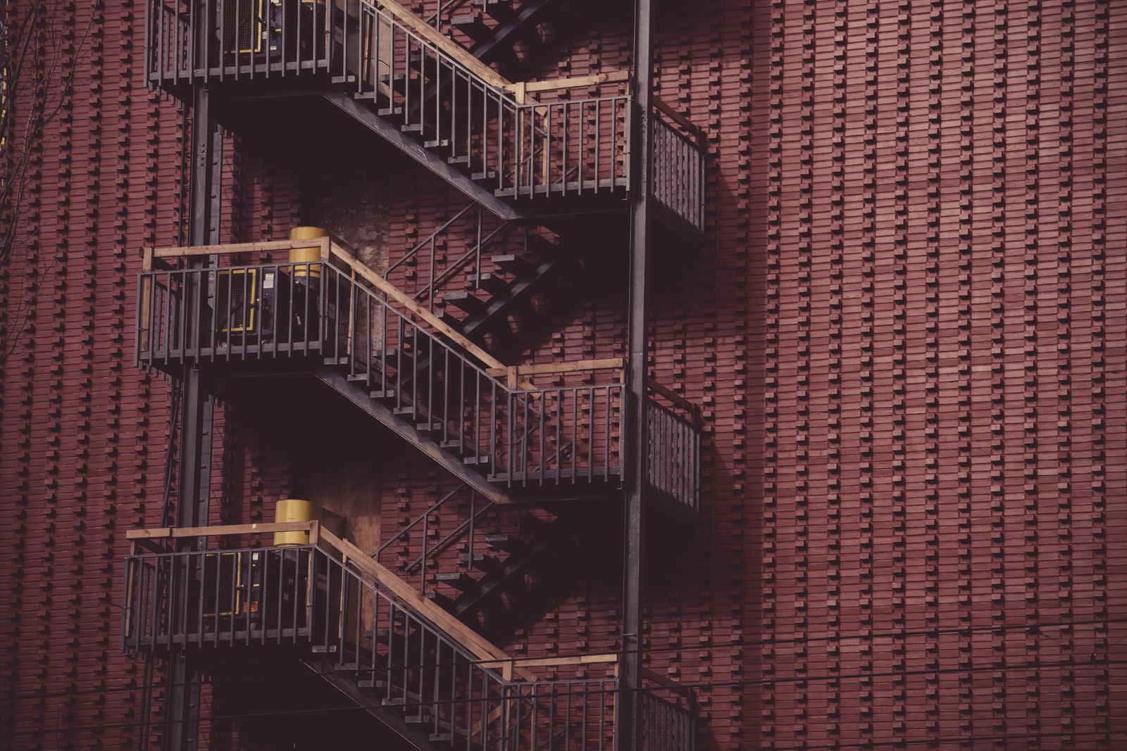 Fire escape ladder on a red brick wall, showcasing urban architecture and design.
