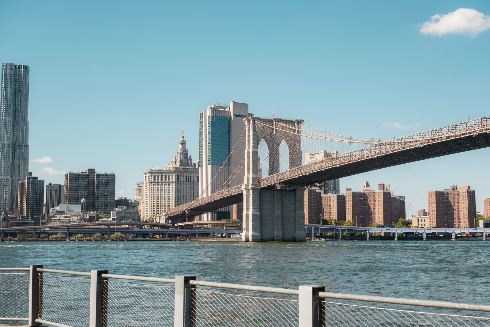 View of the Brooklyn Bridge and Manhattan skyline under a clear sky.